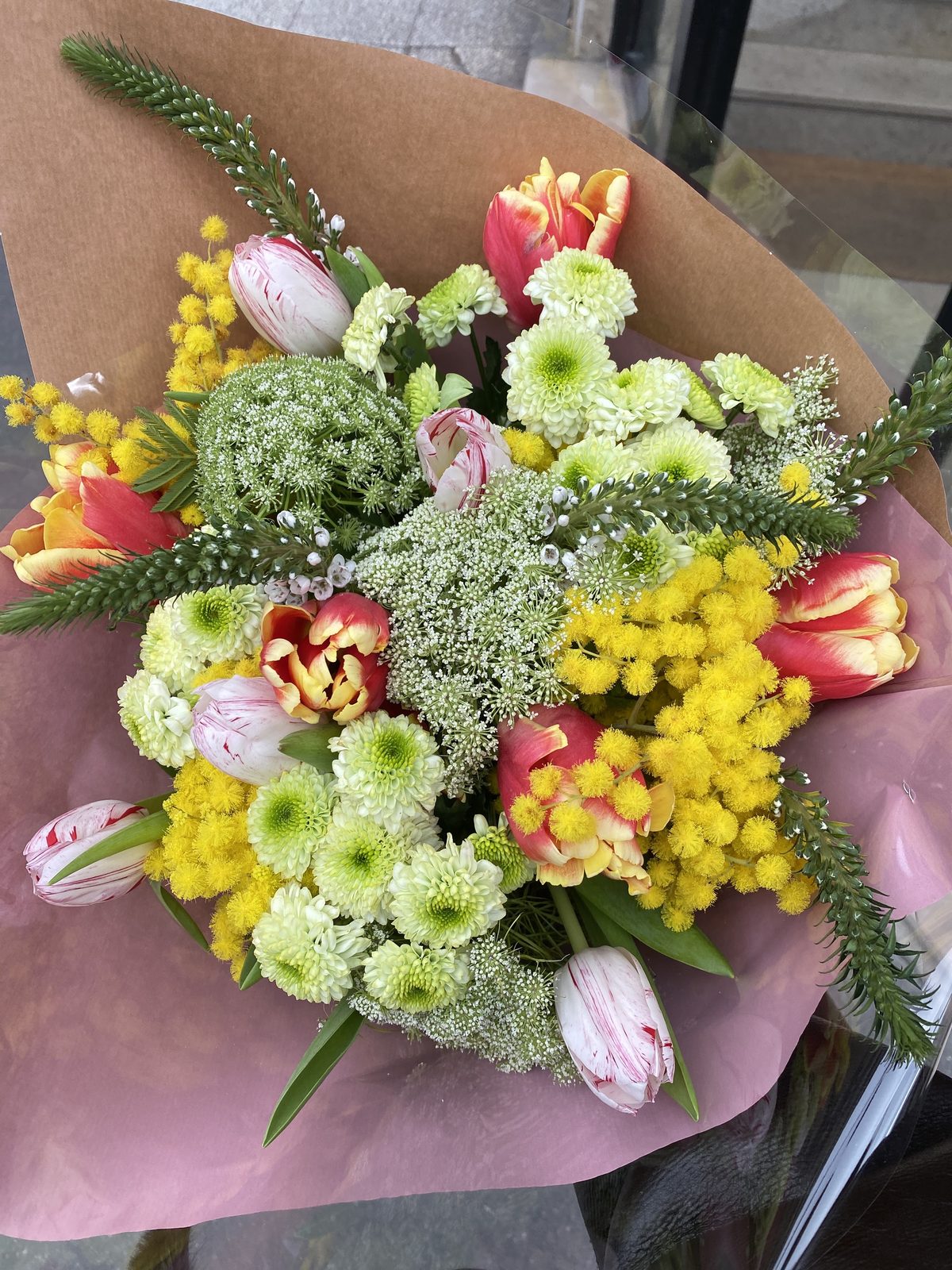 Bouquet de tulipes, mimosa et fleurs blanches dans un papier kraft