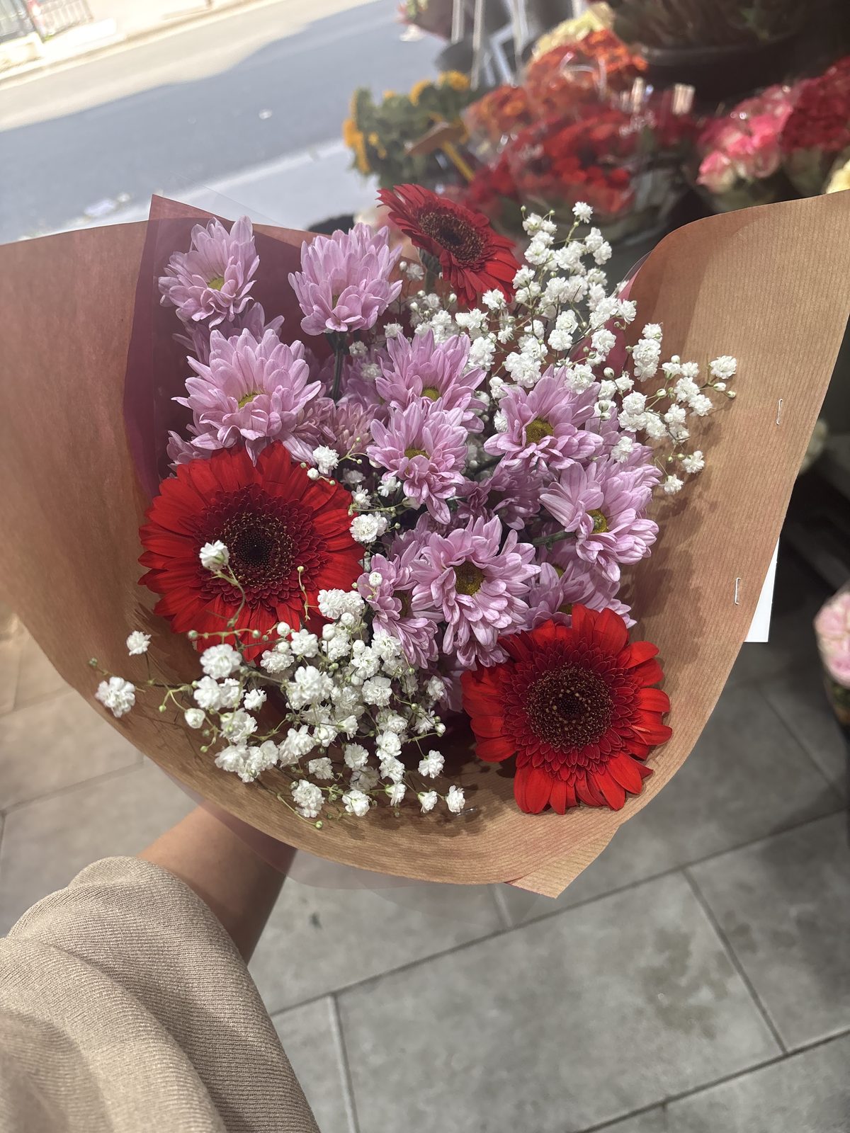 Bouquet de gerberas rouges et de chrysanthèmes mauves dans un papier kraft